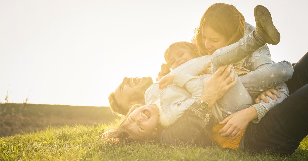 photo of a family rolling on the lawn together laughing
