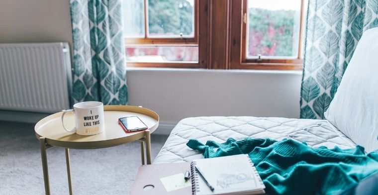 A lounge room with blanket, journal and coffee cup