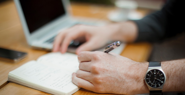 photo of a hand writing on a notebook